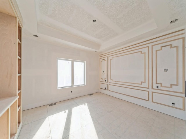 empty room featuring a textured ceiling and a tray ceiling