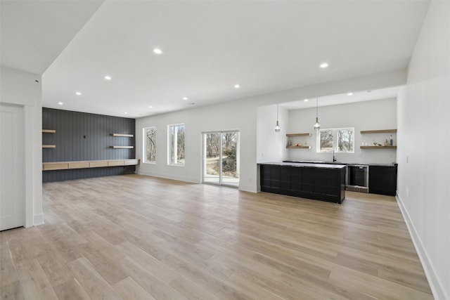 unfurnished living room featuring baseboards, light wood-style flooring, and a healthy amount of sunlight