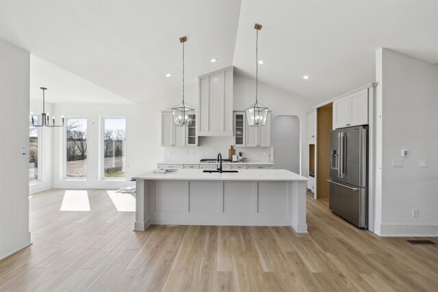 kitchen featuring a sink, a notable chandelier, high end fridge, vaulted ceiling, and light countertops