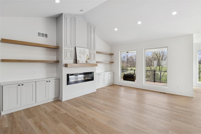 unfurnished living room featuring lofted ceiling, visible vents, a glass covered fireplace, recessed lighting, and light wood finished floors