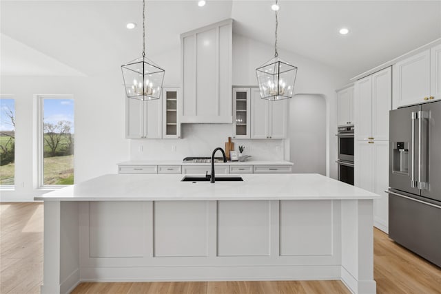 kitchen featuring appliances with stainless steel finishes, a notable chandelier, lofted ceiling, and a sink