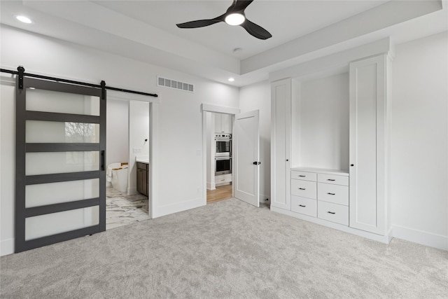 unfurnished bedroom featuring visible vents, recessed lighting, light carpet, and a barn door