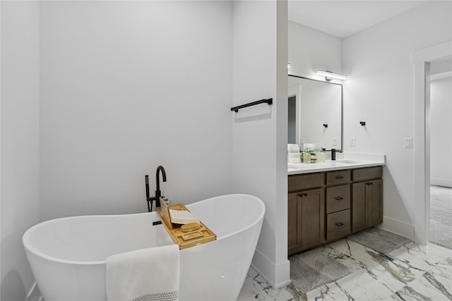 full bath with a sink, a freestanding tub, marble finish floor, double vanity, and baseboards