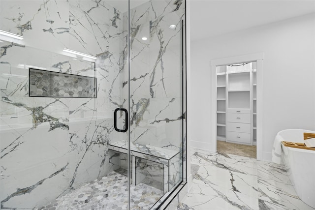 bathroom featuring a freestanding tub, a walk in closet, marble finish floor, and a marble finish shower