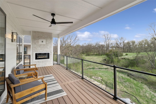 wooden terrace featuring a ceiling fan and an outdoor stone fireplace