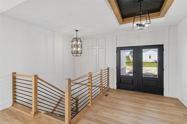 foyer entrance with wood finished floors, french doors, and a notable chandelier