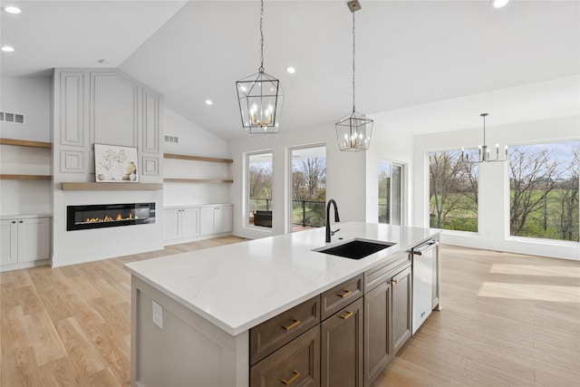 kitchen with lofted ceiling, open shelves, a sink, a chandelier, and dishwasher