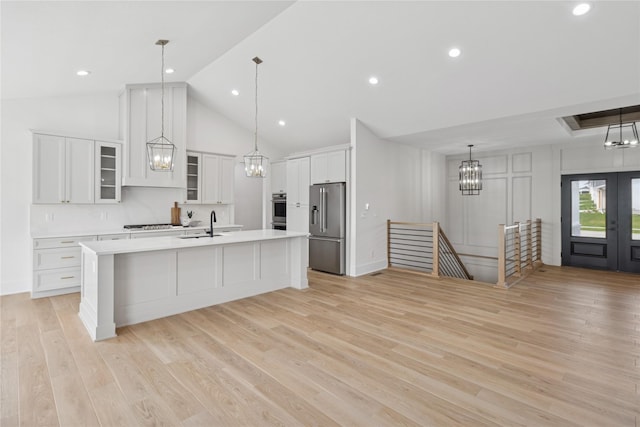 kitchen featuring an island with sink, light wood-style flooring, light countertops, high end refrigerator, and white cabinetry