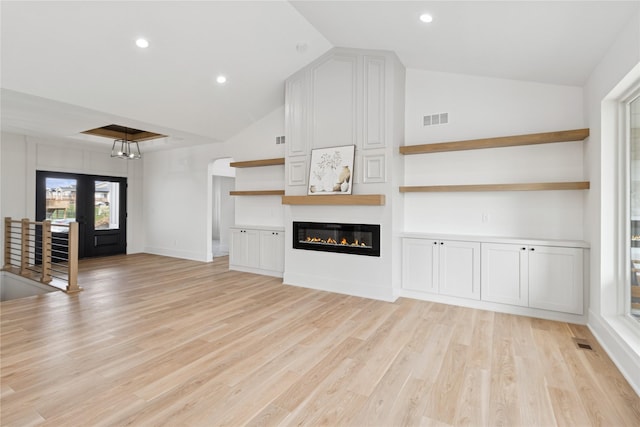 unfurnished living room featuring visible vents, light wood-style floors, and lofted ceiling