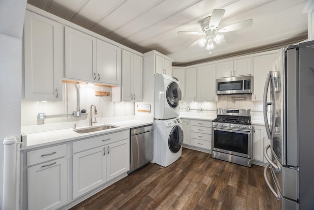 kitchen with sink, stacked washer and dryer, appliances with stainless steel finishes, dark hardwood / wood-style floors, and white cabinets