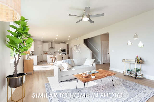 living room with stairs, light wood-style flooring, a ceiling fan, recessed lighting, and baseboards