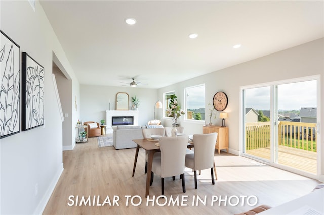 dining room featuring a glass covered fireplace, light wood-style flooring, ceiling fan, baseboards, and recessed lighting