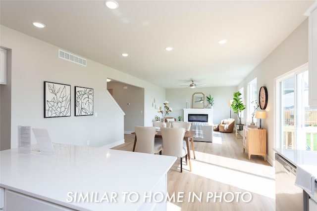 kitchen featuring a glass covered fireplace, light wood-style floors, ceiling fan, dishwasher, and recessed lighting