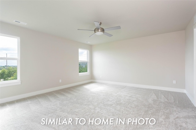 spare room with carpet floors, healthy amount of natural light, baseboards, and ceiling fan