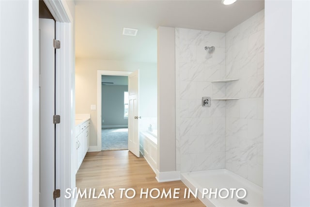 bathroom featuring vanity, tiled shower, wood finished floors, and a garden tub