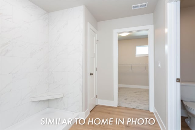 bathroom featuring toilet, wood finished floors, a stall shower, and baseboards