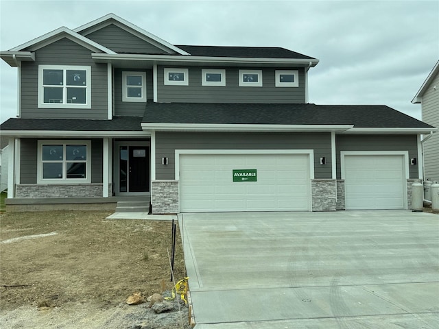 view of front facade featuring stone siding, driveway, and roof with shingles