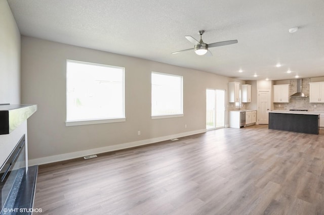6732 Bright St, Johnston, IA 50131 - unfurnished living room featuring ceiling fan, a fireplace, light wood-style floors, recessed lighting, and a textured ceiling