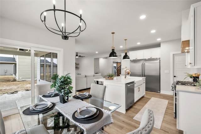 dining room featuring ceiling fan with notable chandelier and light hardwood / wood-style flooring