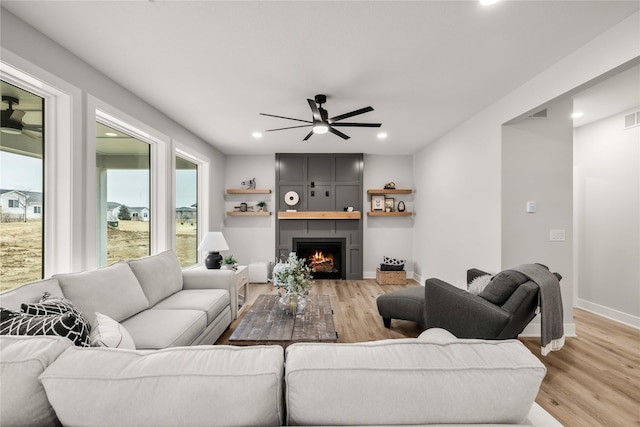 living room with ceiling fan, a fireplace, and light hardwood / wood-style floors