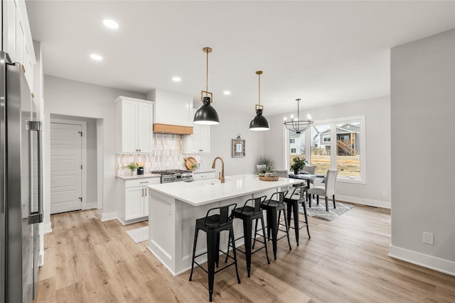 kitchen featuring white cabinetry, tasteful backsplash, stainless steel appliances, and a center island with sink