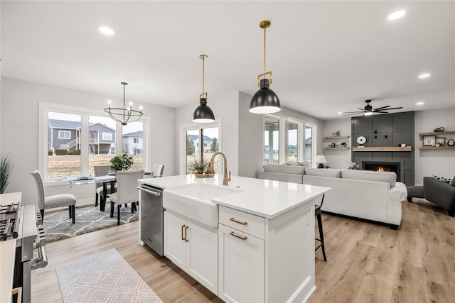 kitchen with sink, white cabinetry, stainless steel dishwasher, an island with sink, and pendant lighting