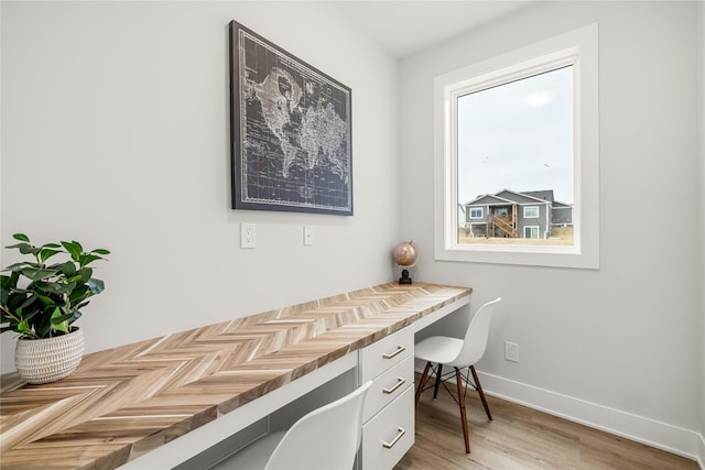 home office with built in desk and hardwood / wood-style floors