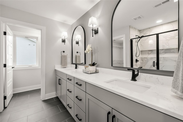 bathroom with a shower with door, vanity, and tile patterned flooring