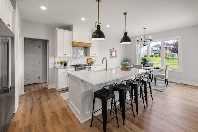 1252 S Radley St, West Des Moines, IA 50266 - kitchen with stainless steel appliances, a sink, a chandelier, light countertops, and light wood finished floors