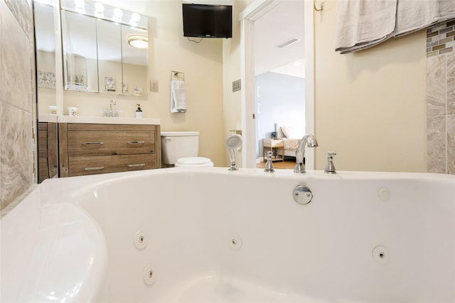 bathroom featuring vanity, a tub to relax in, and toilet