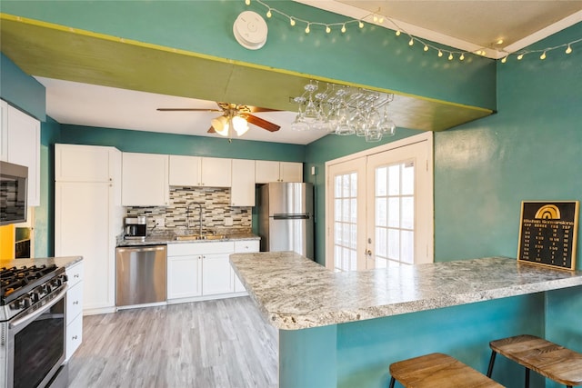 kitchen with white cabinetry, stainless steel appliances, kitchen peninsula, and a kitchen bar