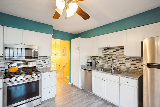 kitchen featuring sink, tasteful backsplash, light wood-type flooring, appliances with stainless steel finishes, and white cabinets