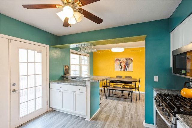 kitchen with stainless steel appliances, white cabinetry, and light wood-type flooring