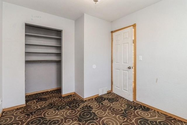 unfurnished bedroom with dark tile patterned flooring and a closet