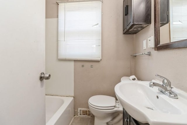 bathroom featuring toilet, vanity, tile patterned floors, and a tub to relax in