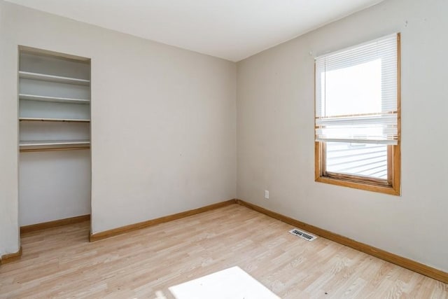 unfurnished bedroom with multiple windows, light wood-type flooring, and a closet