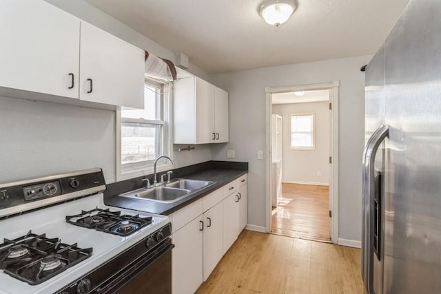 kitchen featuring sink, white cabinets, stainless steel fridge, white gas range oven, and light wood-type flooring