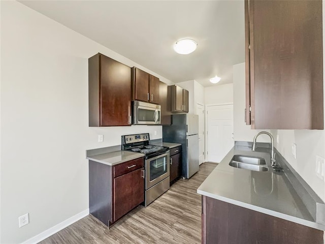 kitchen featuring dark brown cabinetry, sink, stainless steel appliances, and light hardwood / wood-style floors