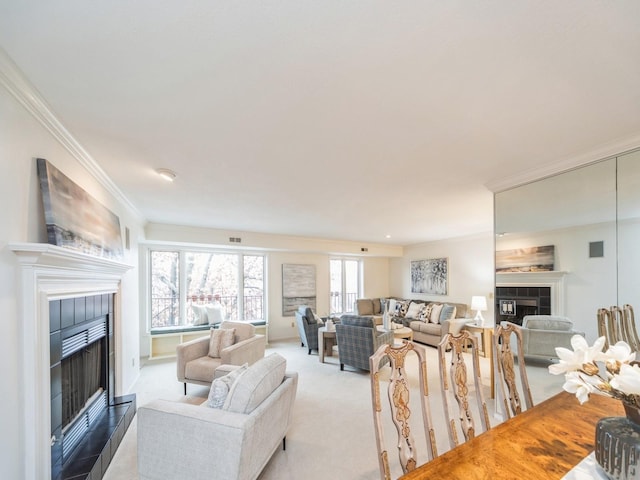 living room with a tiled fireplace, crown molding, and light carpet