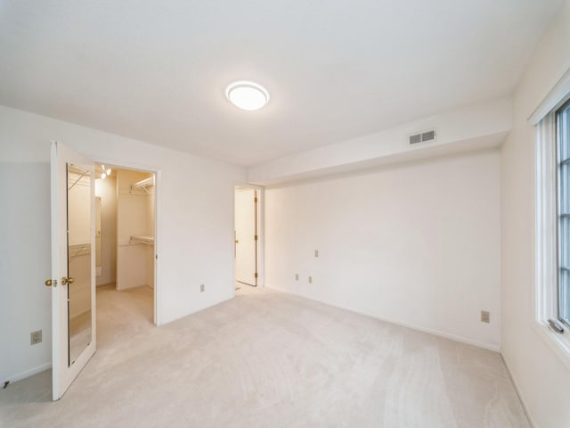 unfurnished bedroom featuring a closet, a spacious closet, and light carpet