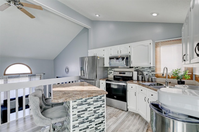 kitchen featuring sink, a breakfast bar area, appliances with stainless steel finishes, lofted ceiling with beams, and white cabinets