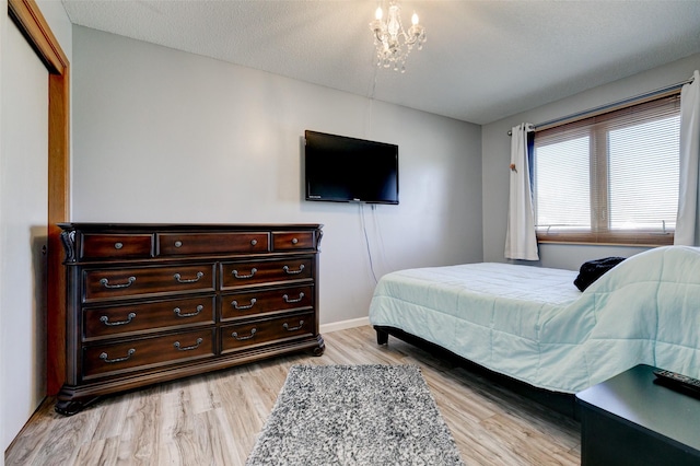 bedroom featuring a textured ceiling, a notable chandelier, and light hardwood / wood-style floors