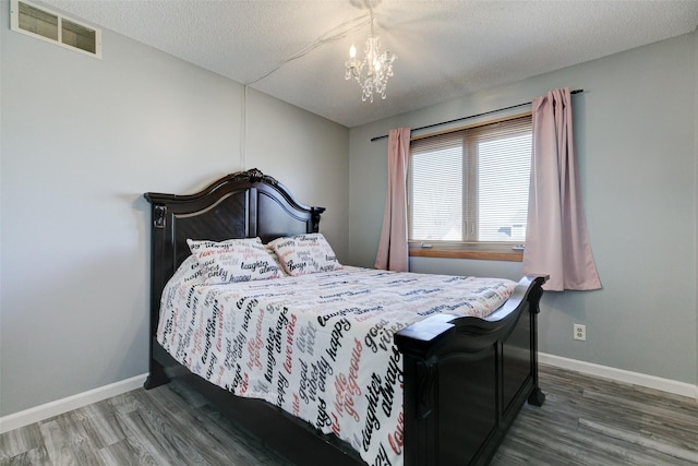 bedroom with dark hardwood / wood-style floors, a chandelier, and a textured ceiling