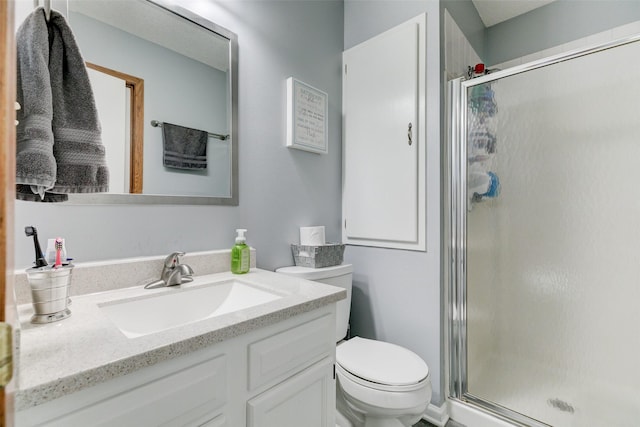 bathroom featuring a shower with door, vanity, and toilet