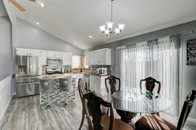 dining room with vaulted ceiling, sink, a notable chandelier, and light wood-type flooring