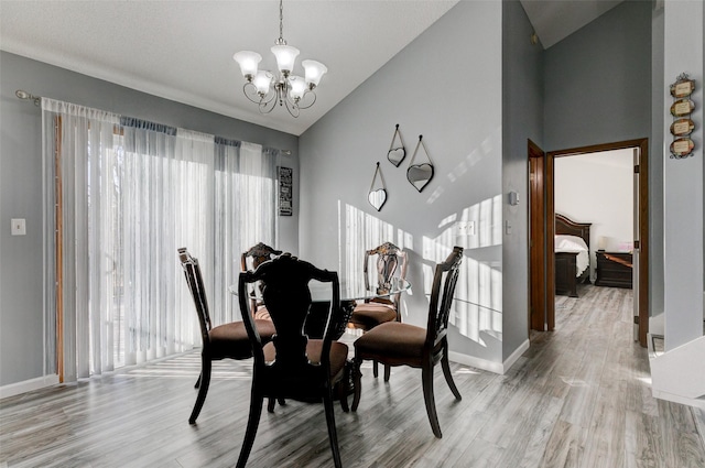 dining space featuring an inviting chandelier, vaulted ceiling, and light hardwood / wood-style flooring