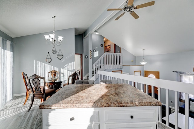 kitchen featuring white cabinetry, vaulted ceiling, hanging light fixtures, and a notable chandelier