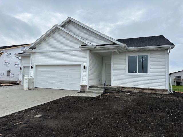 single story home featuring driveway, a shingled roof, and an attached garage