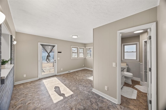 bathroom with vanity, a textured ceiling, toilet, and a healthy amount of sunlight