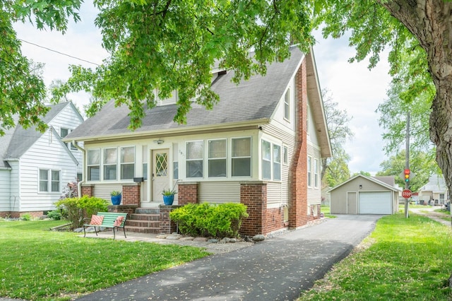 view of front of home featuring a garage, an outbuilding, and a front lawn